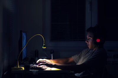 Ein Junge sitzt im Dunkeln vor seinem Computer.