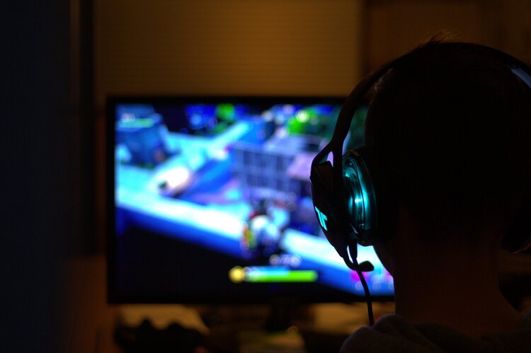 Gamer sitzt mit Kopfhörern vor einem Bildschirm