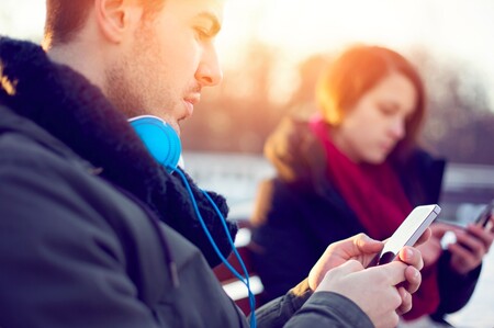 Fake-Profile und Bildrechte im Netz Junger Mann und junge Frau schauen ernst auf ihre Smartphones