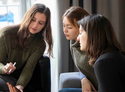 Drei junge Frauen schauen gemeinsam auf ein Tablet