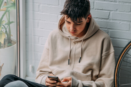 Cybermobbing ist strafbar und sollte daher immer gemeldet werden. Zu sehen ist ein Jugendlicher, der auf sein Handy schaut.