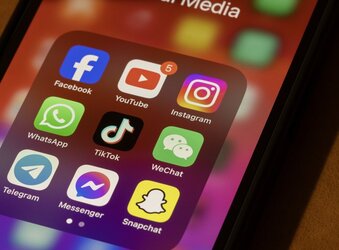 Das Display eines Handys mit den Icons der großen Social Media Plattformen wie TikTok, YouTube, Instagram und WhatsApp