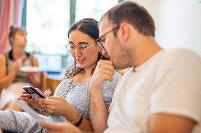 Eine junge Frau und ein junger Mann schauen auf ein Handy