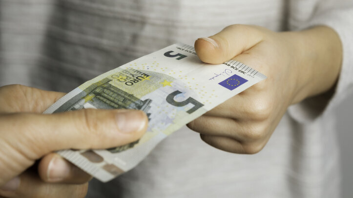 Ein Junge bekommt 5 Euro Schein von einem Mann