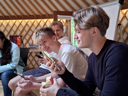 drei Jugendliche sitzen zusammen. einer hält ein Handy.