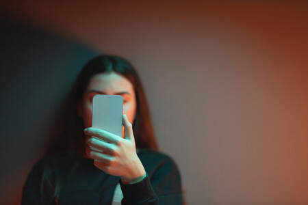 Ein Mädchen schaut auf ihr Smartphone - ihr Gesicht ist dahinter verborgen.