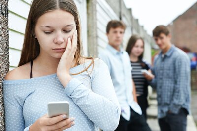 Junges Mädchen guckt besorgt auf ihr Handy