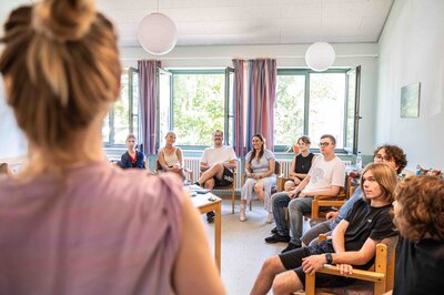 Junge Menschen sitzen gemeinsam im Stuhlkreis