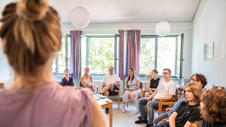 Junge Menschen sitzen gemeinsam im Stuhlkreis