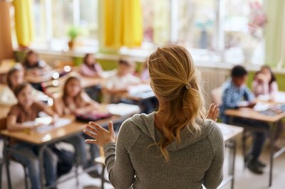 Eine Lehrerin steht vor ihrer Klasse in der Grundschule
