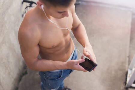 Ein junger Mann mit nacktem Oberkörper schaut auf sein Handy