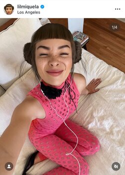 Eine KI-Influencerin posiert auf dem Bett und schaut in die Kamera.