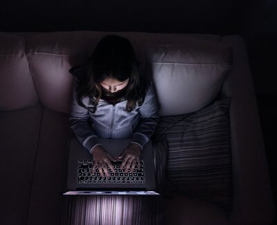 Ein Mädchen sitzt in einem dunklen Raum vor ihrem Laptop. Ein Mädchen sitzt in einem dunklen Raum vor ihrem Laptop.